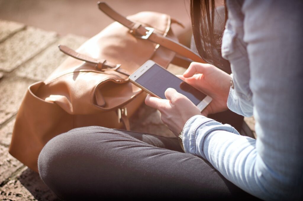 A woman sits while looking at her smart phone.