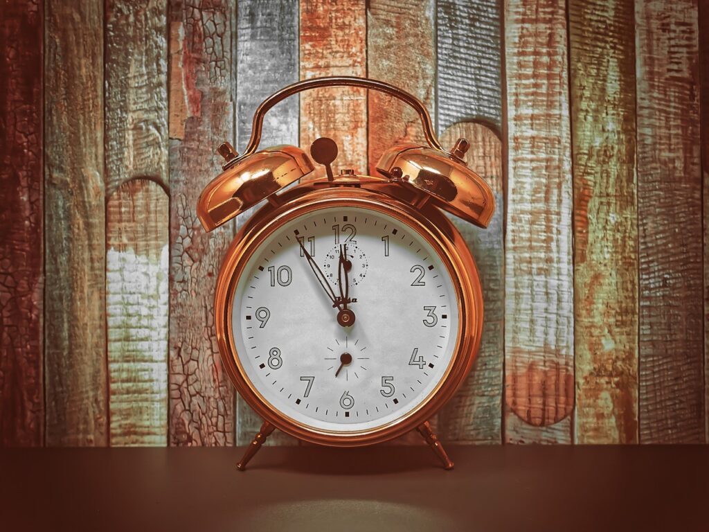A metal alarm clock in front of a wooden panel background