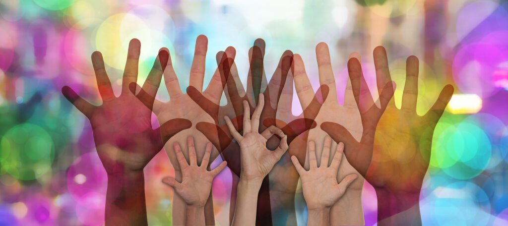 Many hands raised in front of a colorful background.